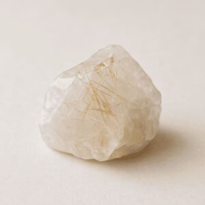 Transparenter Rutilquarz-Rohstein mit goldenen Nadeln auf hellem Hintergrund – steht für Energieverstärkung, Fokus und spirituelle Klarheit
